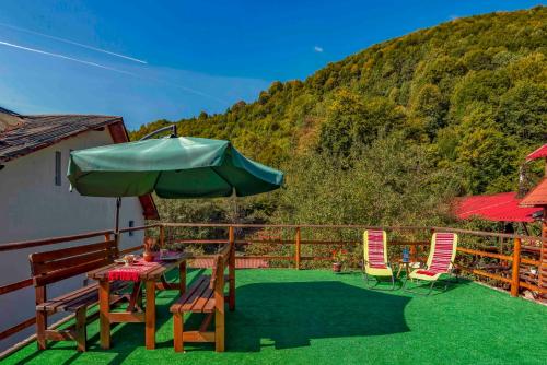 a patio with a table and chairs and an umbrella at Raiul de pe Rau in Moroeni