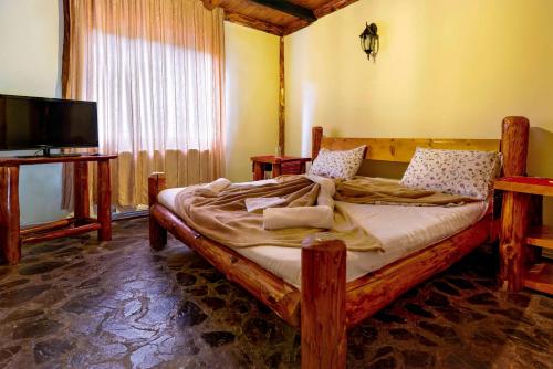 a bedroom with a large wooden bed with a television at Raiul de pe Rau in Moroeni