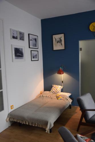 1 dormitorio con cama y pared azul en Bleak House - Bauhaus home in greener Budapest, en Budapest