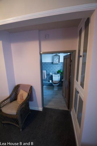 a room with a hallway with a chair and a bathroom at Lea House Bed and Breakfast in Ross on Wye