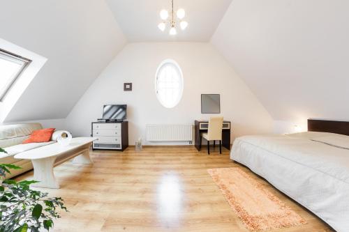a white attic bedroom with a bed and a desk at Villa A. Malka in Poděbrady
