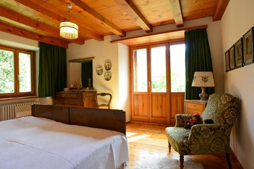 a bedroom with a bed and a chair and windows at Bed and Breakfast da Käthy Agriturismo in Grono