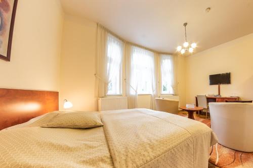 a bedroom with a bed and windows and a desk at Villa A. Malka in Poděbrady