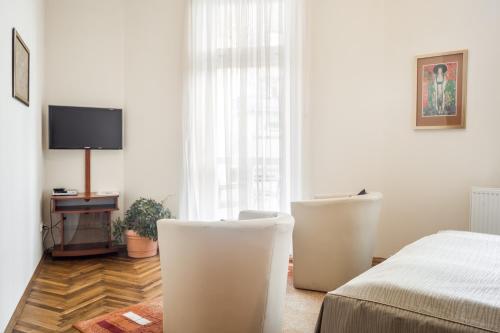 a bedroom with a bed and two white chairs at Villa A. Malka in Poděbrady