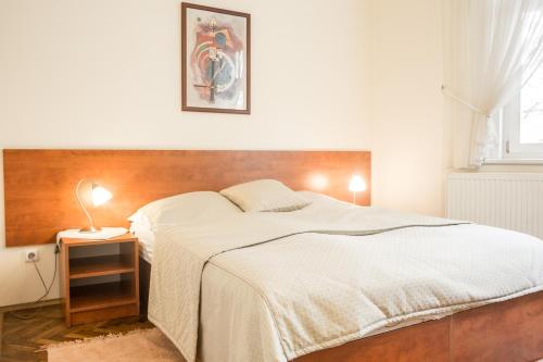 a bedroom with a white bed with a wooden headboard at Villa A. Malka in Poděbrady