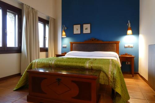 a bedroom with a bed with a green blanket at Hospederia de Loarre in Loarre