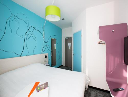 a bedroom with a white bed and a colorful wall at ibis Styles Strasbourg Centre Petite France in Strasbourg