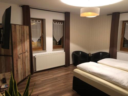 a room with two beds and chairs and windows at Hotel garni Zum Rebstock in Naumburg