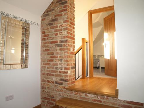 a brick wall in a room with a stairway at New Bury Cottage near Goodwood in Chichester