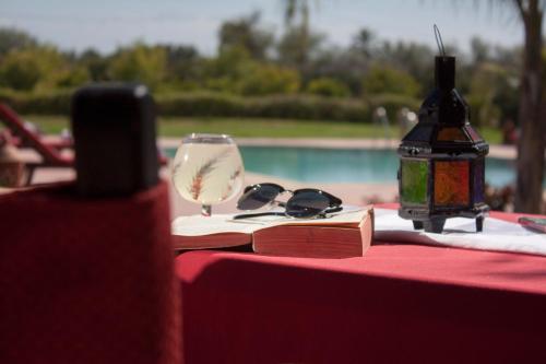 a table with a book and a wine glass and a bottle at Teacook Marrakech in Ouled el guerne