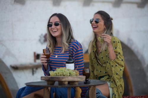 two women sitting next to a table with drinks at Wish Cappadocia in Uchisar