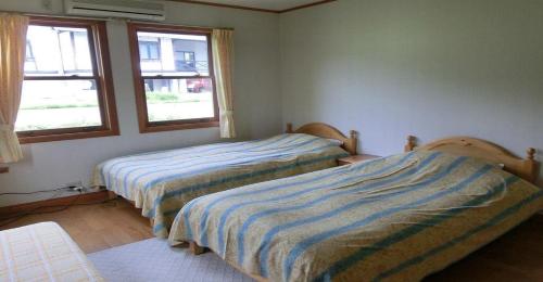 two beds in a room with two windows at Pension Come Relaxing Western-style room- Vacation STAY 14977 in Minami Uonuma