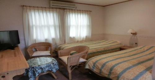 a hotel room with two beds and a television at Pension Come Western style room with bath and toilet - Vacation STAY 14966 in Minami Uonuma