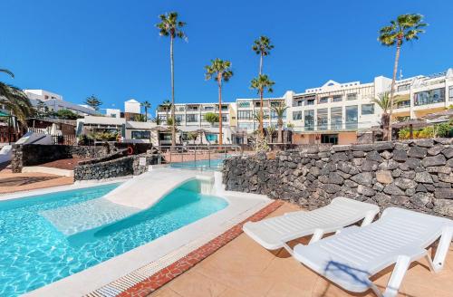 basen z 2 leżakami i budynek w obiekcie Marisol Apartment Wifi Stunning Pool w Costa Teguise