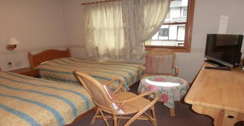 1 dormitorio con 2 camas, escritorio y TV en Pension Come Western style room with bath and toilet - Vacation STAY 14966 en Minami Uonuma