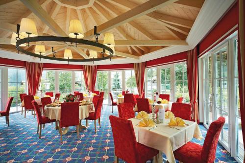 una sala da pranzo con tavoli, sedie e lampadario a braccio di Hotel Hubertus a Neukirchen am Grossvenediger