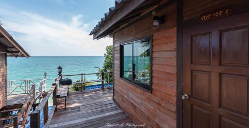 a wooden house with a door and the ocean at Sangthian Beach Resort in Ko Samed