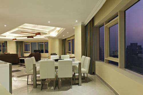 a dining room with a table and white chairs at Magnum Hotel & Suites West Bay in Doha