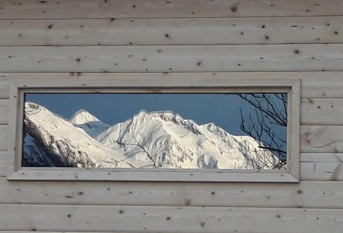 a snow covered mountain seen through a window of a building at Chalet Solneige in Vaujany