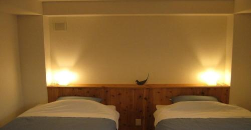 京都市にあるGuesthouse Hyakumanben Cross twin room / Vacation STAY 15395のベッド2台 壁に照明2つが備わる客室です。