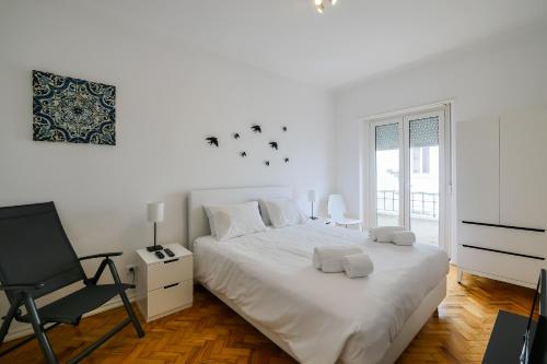 a white bedroom with a bed and a chair at Lisboa: Cabo in Lisbon