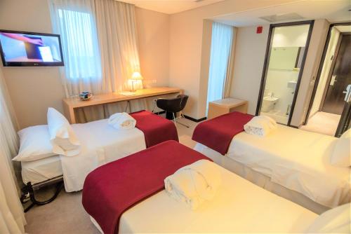a hotel room with three beds and a television at Salto Hotel y Casino in Salto