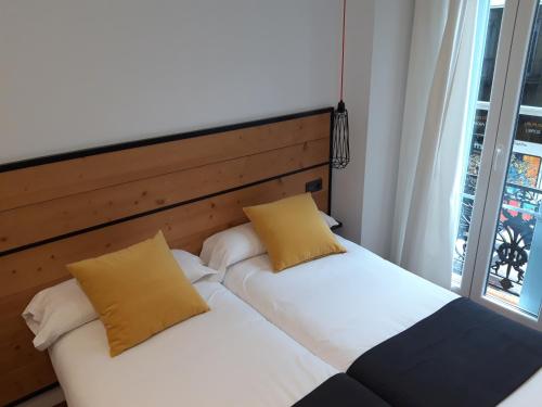 two twin beds in a room with a window at Pensión La Perla in Donostia-San Sebastián
