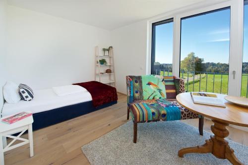 een slaapkamer met een bed, een tafel en een stoel bij Herzberger Ferienwohnungen in Scheidegg