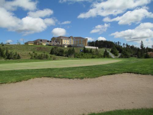 a golf course with a house on top of a hill at The Wilds at Salmonier River in Holyrood