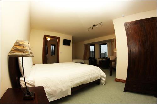 a bedroom with a bed and a desk with a lamp at All the Twos Lodge in Clifden