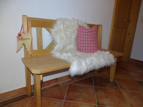 a wooden chair with a white furry pillow on it at Anna's Appartement in Alpbach