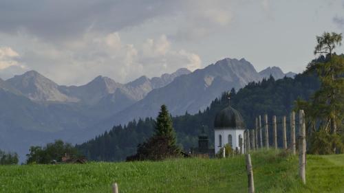 a church in a field with mountains in the background at Ferienwohnung Mathias Kennerknecht in Fischen