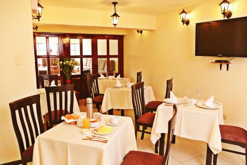 a restaurant with white tables and chairs and a flat screen tv at Apart Hotel Caminos del Inca in Lima