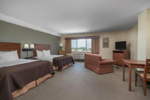 a hotel room with two beds and a chair at AmericInn by Wyndham Newton in Newton