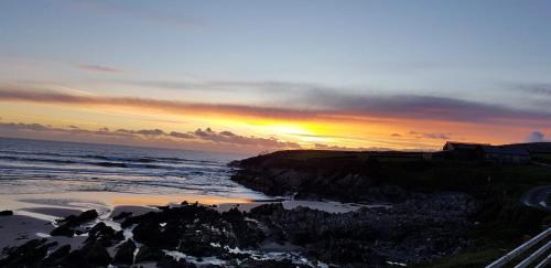 a sunset over a beach with the ocean at Skellig Port Accomodation - 2 Bed Apartment in Portmagee