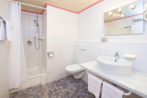 ein weißes Bad mit einem Waschbecken und einem WC in der Unterkunft Landhotel Herzberger garni Zimmer & Ferienwohnungen in Scheidegg