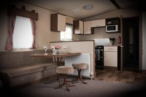 una piccola cucina con tavolo e sedie di 3 Bed Static Caravan @ Hoburne Devon Bay a Paignton