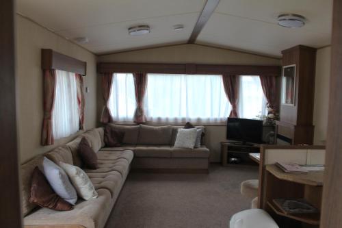a living room with a couch and a tv at 3 Bed Static Caravan @ Hoburne Devon Bay in Paignton
