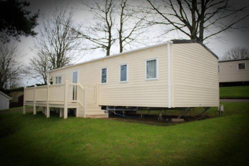 a large white house sitting on top of a yard at 3 Bed Static Caravan @ Hoburne Devon Bay in Paignton