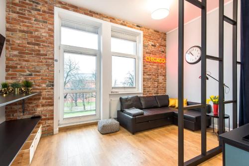 a living room with a couch and a brick wall at Bliss Apartments in Poznań