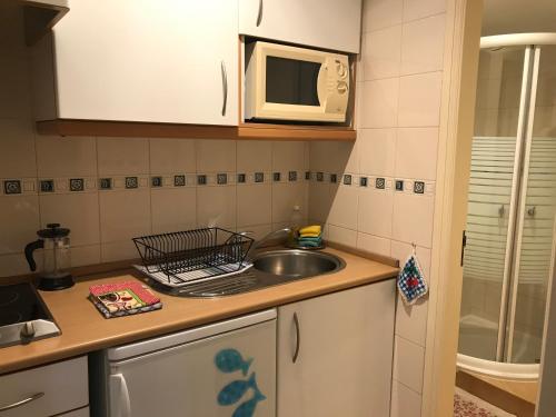 a small kitchen with a sink and a microwave at Hospedaria Bernardo in Ericeira
