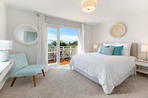 a white bedroom with a bed and a balcony at Eight on Church - near Mudbrick & Cable Bay in Oneroa