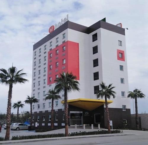 a large building with palm trees in front of it at Hotel Hi ! Torreon Aeropuerto-Galerías in Torreón