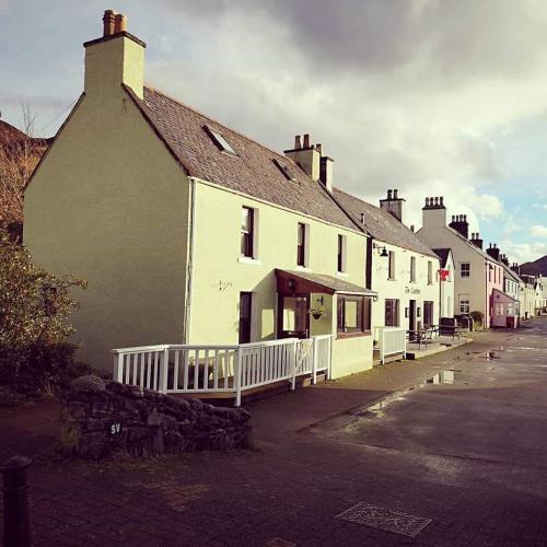 a row of white buildings on a street at Eilean Donan View in Dornie