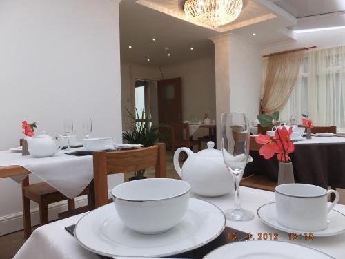 a dining room with white cups and plates on a table at Jessamine House Hotel in Gravesend