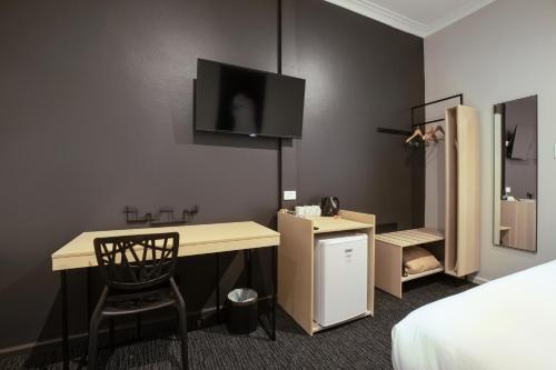 a room with a desk and a tv on the wall at Nightcap at the Charles Hotel in Wollongong