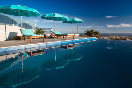 a swimming pool with two chairs and umbrellas at "NEW" Deluxe designer Villa Infinity, with Panoramic sea views,own exclusive heated private pool, subtropical gardens in Tías