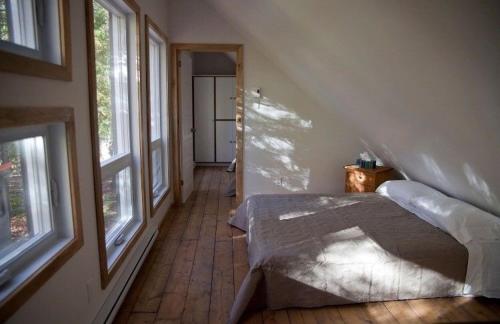 a bedroom with a bed in a room with windows at Le Cocon Orford Domaine Cheribourg in Magog-Orford