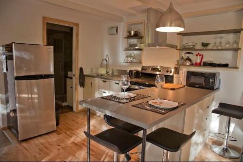 a kitchen with a refrigerator and a table with chairs at Le Cocon Orford Domaine Cheribourg in Magog-Orford