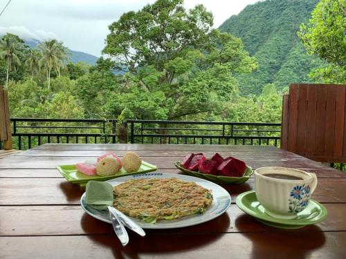 a table with a plate of food and a cup of coffee at Sugi Gede Homestay in Singaraja